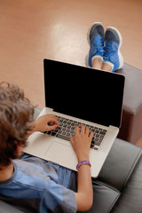 Latino boy sitting on sofa with laptop computer