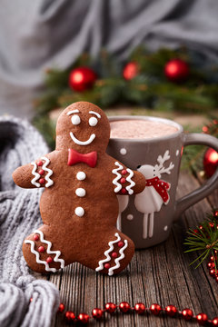 Hot chocolate or cocoa beverage with cinnamon and gingerbread man cookie in new year tree decorations frame on vintage wooden table background. Homemade traditional celebration dessert recipe.