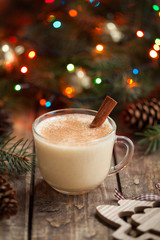 Eggnog traditional christmas holiday egg, vanilla, rum alcohol liqueur drink preparation recipe in two glass cups with cinnamon sticks on wooden vintage table. Colorful bokeh background. shallow depth
