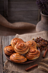 Sweet cinnamon bun rolls danish christmas delicious dessert on vintage wooden table background. Traditional swedish kanelbullar baked pastry