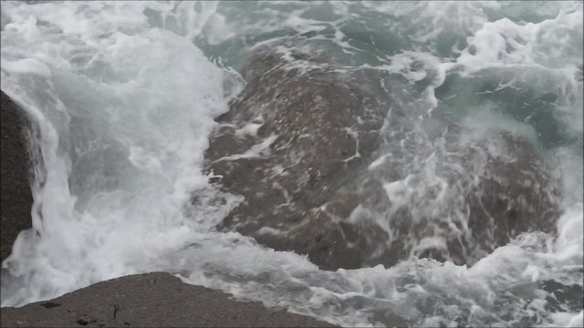 Film einer tosenden Brandung zwischen Felsen als closeup in Vogelperspektive