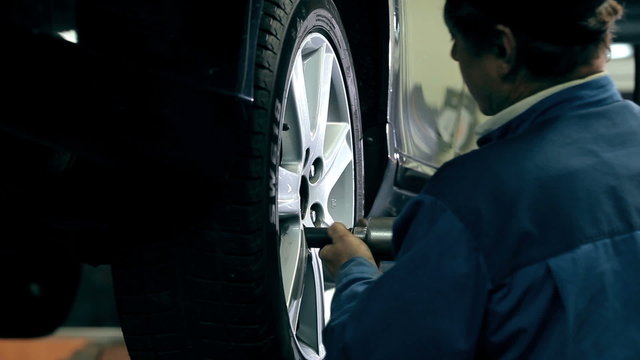 Mechanic fasten the wheel on the car