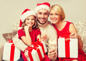 smiling family holding gift boxes and sparkles