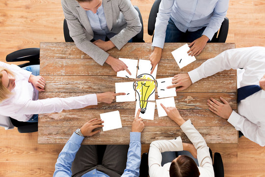 close up of business team with light bulb puzzle