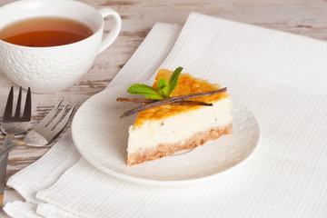 Vanilla cheesecake on a white plate and cup of tea