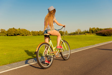sexy shapely girl with hat and mini shorts ride a bicycle