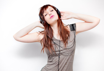 Mujer joven escuchando música con auriculares en fondo blanco. Estilo de vida