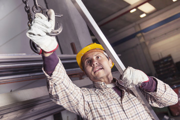 young metalworker hooks a steel tube to lift