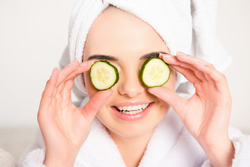 Nice young woman with cucumbers on eyes and towel on her head
