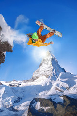 Naklejka na ściany i meble Snowboarder jumping against Matterhorn peak in Switzerland
