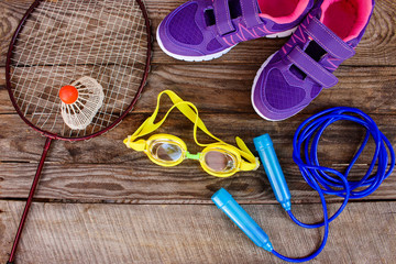 Sports equipment: the birdie is on the racket, skipping rope, swimming goggles and sneakers on...