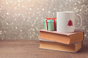 Christmas celebration with cup and gift box on books over bokeh background - Powered by Adobe