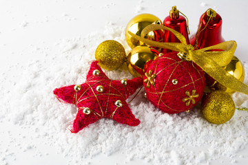 Christmas red and gold ornament balls, bells, star in snow on a white background