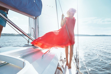 Beautiful young sexy brunette girl in a dress and makeup, summer trip on a yacht with white sails on the sea or ocean in the Gulf marine of the wind and the breeze in the sun tans romantic