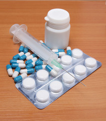 Medical syringe and pills on table