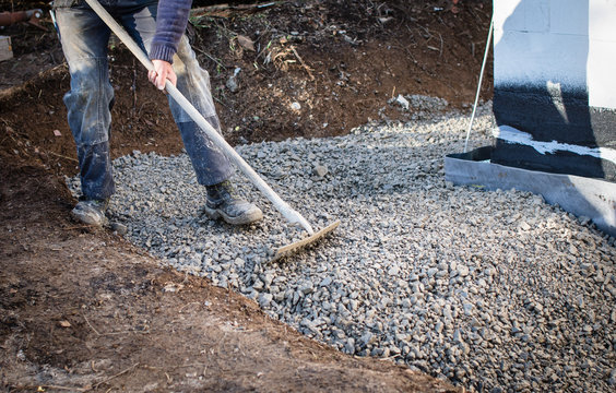 Construction worker spreading gravel, selective focus.
