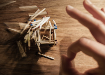 A hand destroying matches tower - metaphor of higher force omnipotence and human helplessness