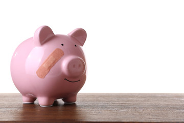 Piggy Bank with adhesive bandage wooden table, on white background