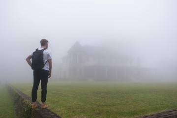 Teenager Walking Home across grass lawn covered in cloud mist 