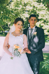 Beautiful bride and groom on the background of green foliage in summer sunny day
