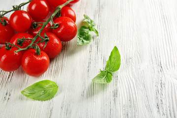 Cherry tomatoes with basil on wooden table close up