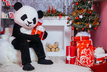 A man dressed as a panda holding a Christmas gift