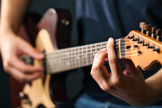 Young musician playing acoustic guitar close up