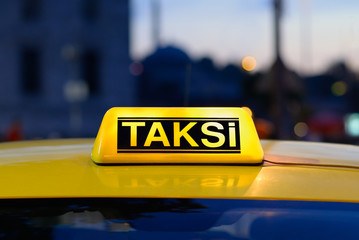 Macro view of yellow turkish taxi sign on car at night.