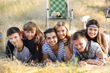 A group of happy smiling friends lying in the grass outdoors