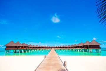 Fototapeta na wymiar Water bungalows and wooden jetty on tropical island in Indian Ocean