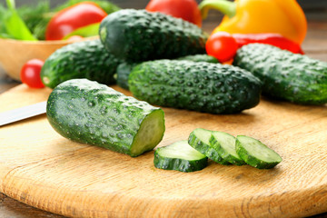 Composition of cucumbers, tomatoes and sweet peppers circles on wooden background