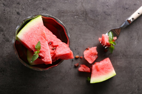 Sliced watermelon in metal bowl on grey background, close up