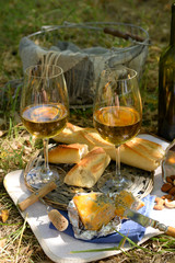 Beautiful composition of wine, cheese, almonds and baguette, outdoors