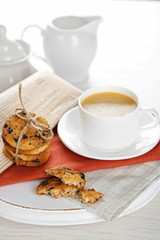 Cup of coffee and pile of tasty cookies with chocolate crumbs on white wooden table