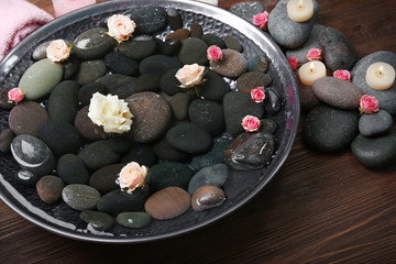 Spa composition of flowers and stones in water on wooden background