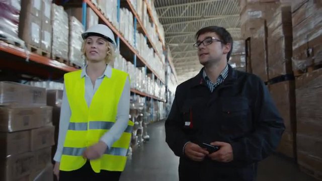 Male Worker and Female Manager are Walking through Logistic Warehouse