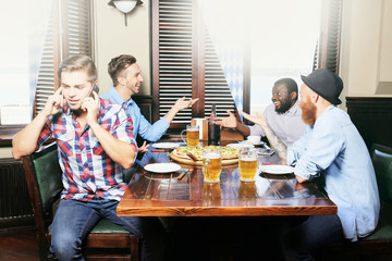 Young men drinking beer and talking in cafe