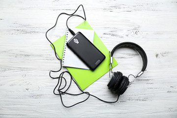 Headphones with notebooks and smartphone on wooden table