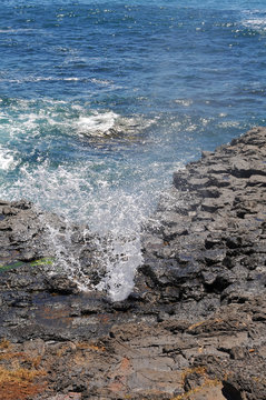 Spray from a small blowhole in coastal rocks.