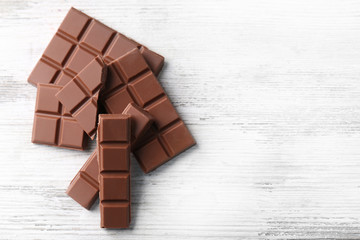 Black chocolate pieces on color wooden background