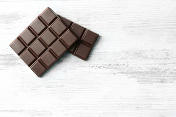 Milk chocolate pieces on color wooden background