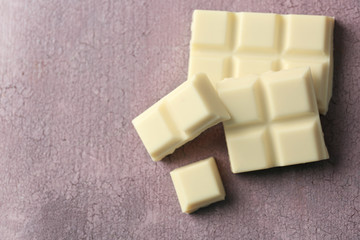 White chocolate pieces on color wooden background