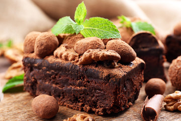 A piece of chocolate cake with walnut and mint on the table, close-up