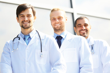 Handsome smiling doctors standing in a row near the clinic