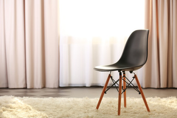 Stylish conception with black chair on light room background