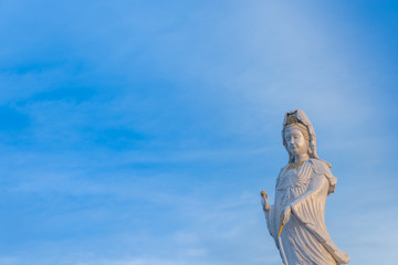 The statue of Guanyin with blue sky. Chinese goddess statue. Places of Worship