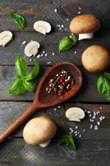 Fresh mushrooms, basil leaves and spices on wooden background
