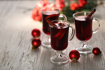 Mulled wine with red Christmas toys on wooden table