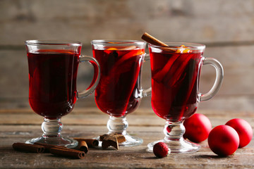 Mulled wine with red Christmas toys on wooden table