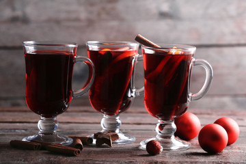 Mulled wine with red Christmas toys on wooden table